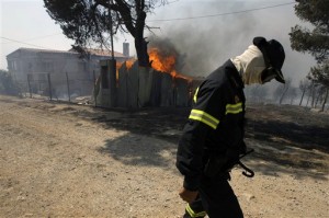 A firefighter walks by a burning building in Dioni, 40 kilometers (25 miles) east of Athens, Greece, Monday, Aug. 24, 2009. An overnight drop in gale-force winds offered hard-pressed Greek firefighters a brief respite Monday after wildfires raged unchecked for two days north of Athens, burning houses and swathes of forest while forcing thousands to flee their homes. (AP Photo/Petros Giannakouris)