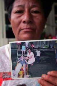 Dolores Morales holds a photo of her nineteen-year-old son Pedro who died of a cancerous tumor at her home in Sacha Central