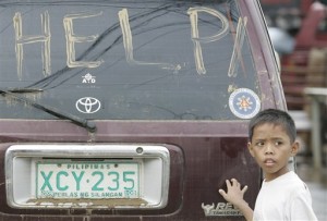 A boy stands beside a sign on a vehicle which was written in mud as residents slowly return to their homes in suburban Marikina city, east of Manila, Philippines on Monday Sept. 28, 2009. Many Filipinos tried to rebuild their lives Monday after saving little more than the clothes they wore in a tropical storm that prompted the capital's worst flooding in more than four decades. (AP Photo/Aaron Favila)