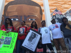 Families of those killed by police stand in front of mural of police victim Freddie Gray./Photo by John Zangas